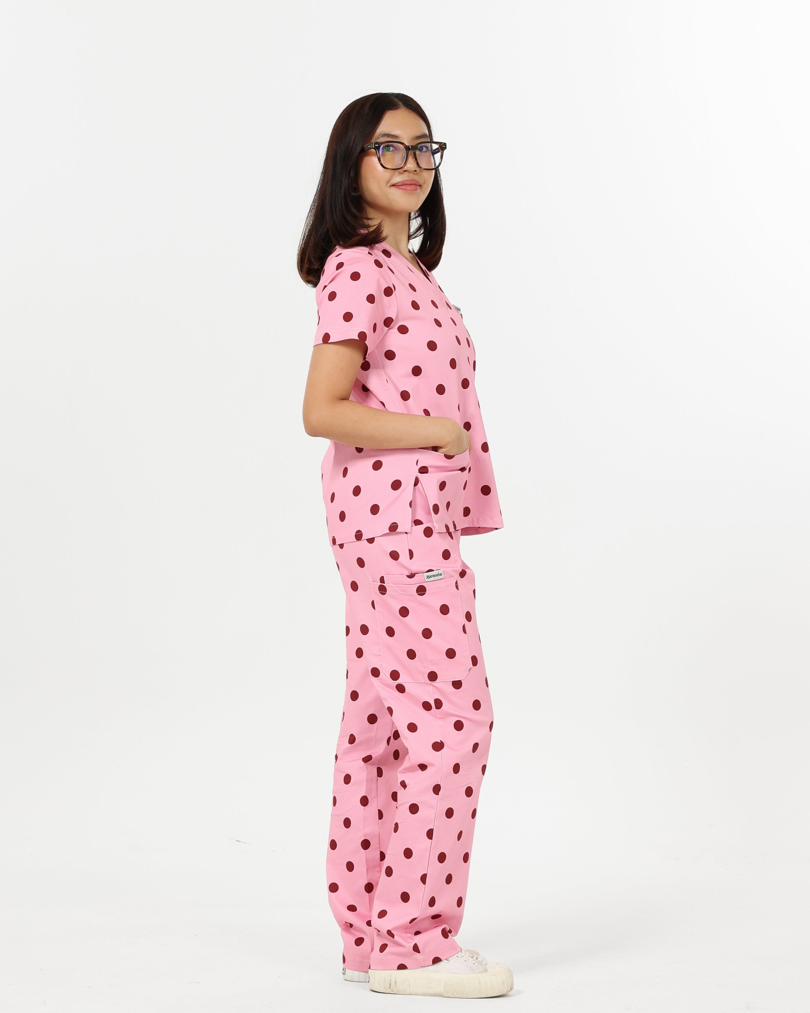 Woman wearing a pink polka dot scrub set on a white background