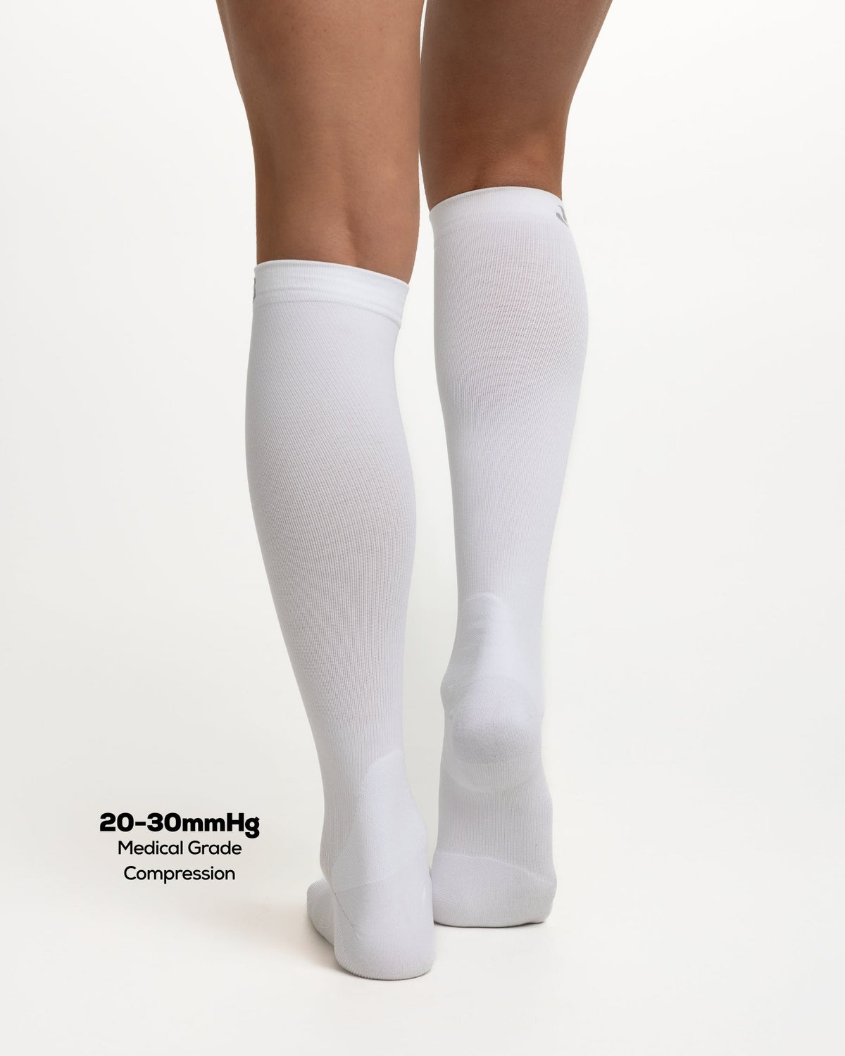 White knee-high compression socks worn on a model's legs, shown from the back against a clean white background with text reading '20-30mmHg Medical Grade Compression'.