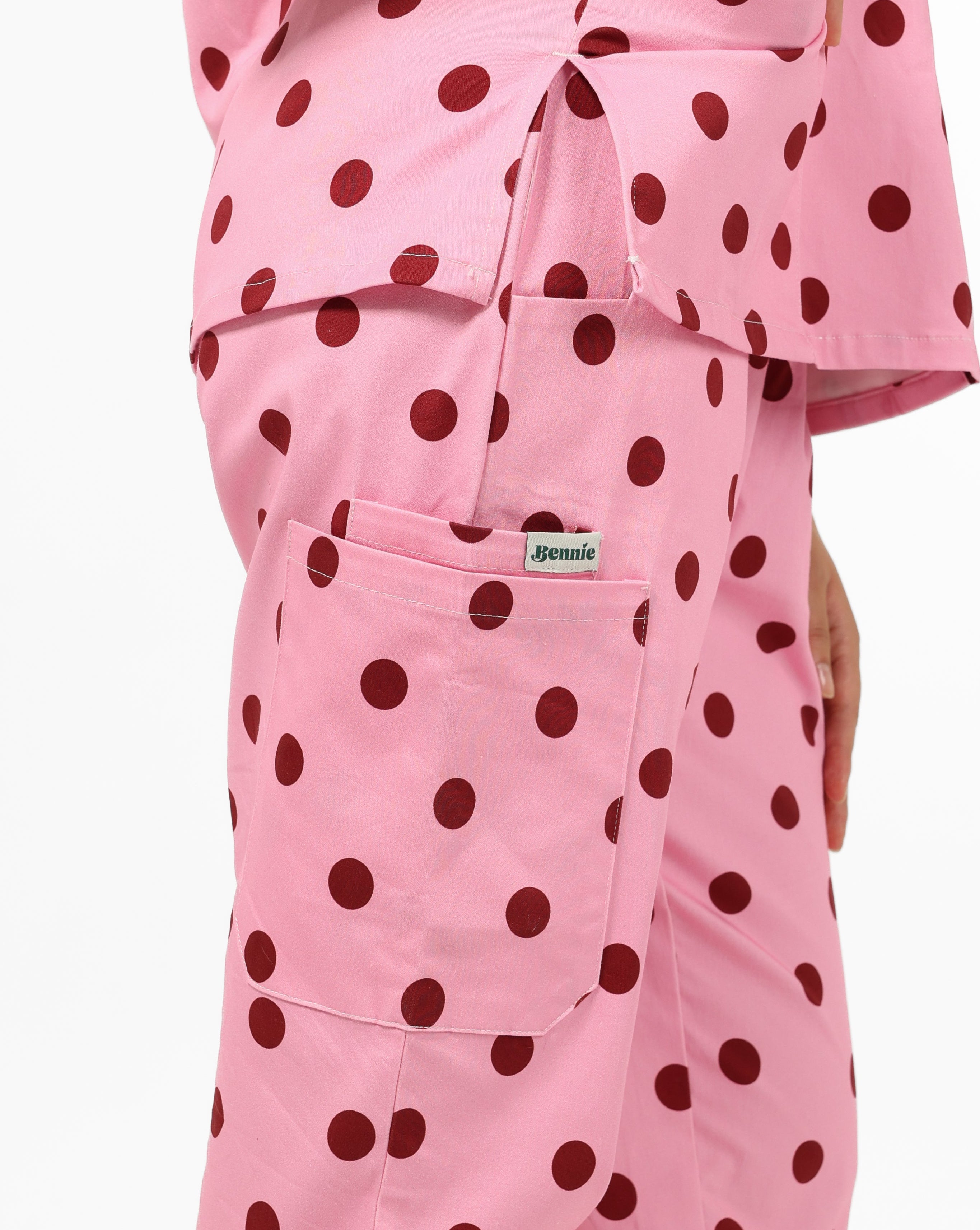 Pink scrub set with red polka dots on a white background