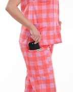 Close-up of Bennie Athena Scrub Set in pink checkered print, showing functional pocket detail holding a phone. 
