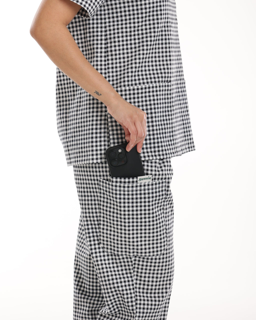 Side view of Bennie Frankie Scrub Set in black and white gingham, featuring functional pocket detail holding a phone.