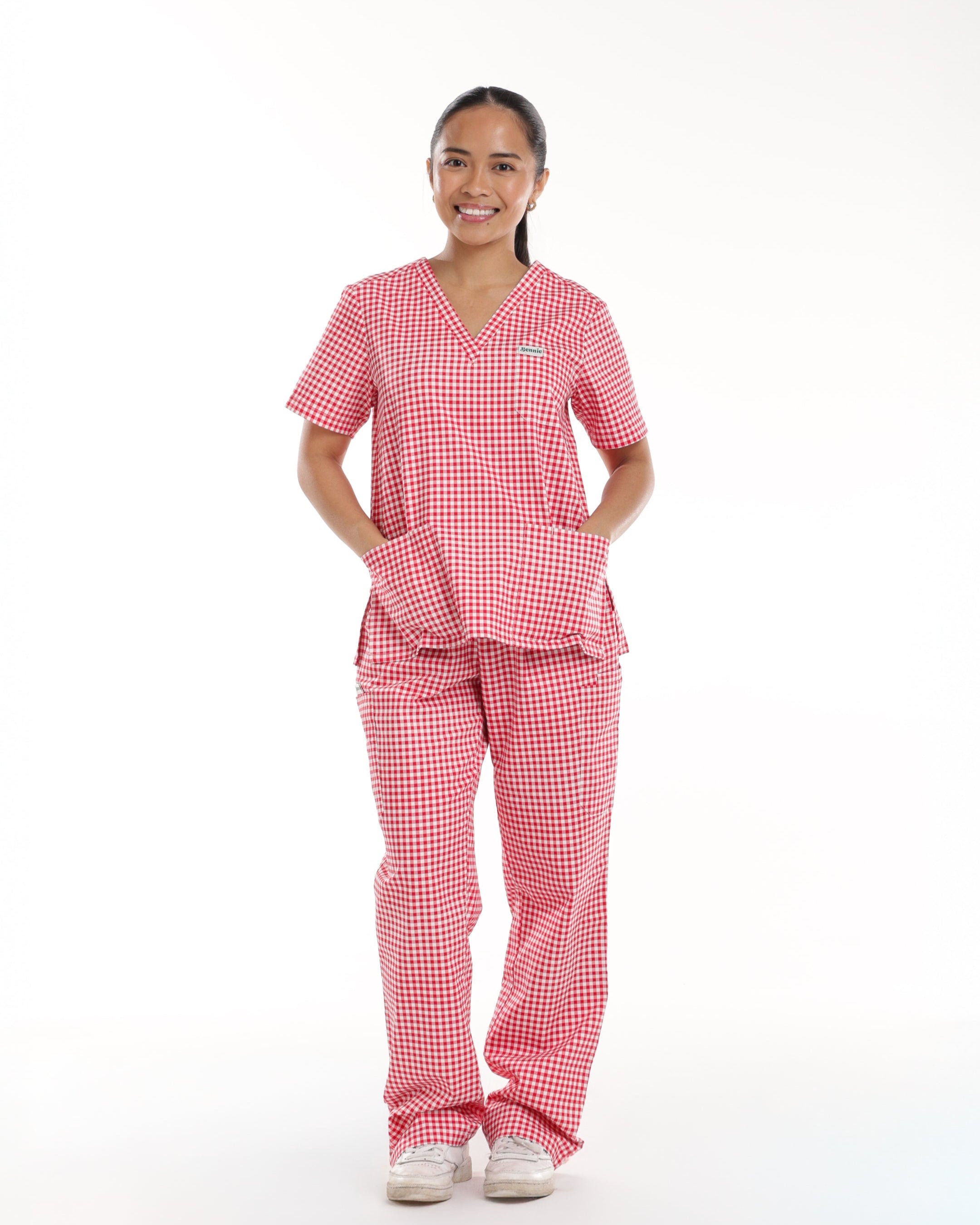 Model wearing Bennie Ruby Scrub Set in red checkered gingham, front view showcasing short sleeve scrub top and straight-leg pants. 