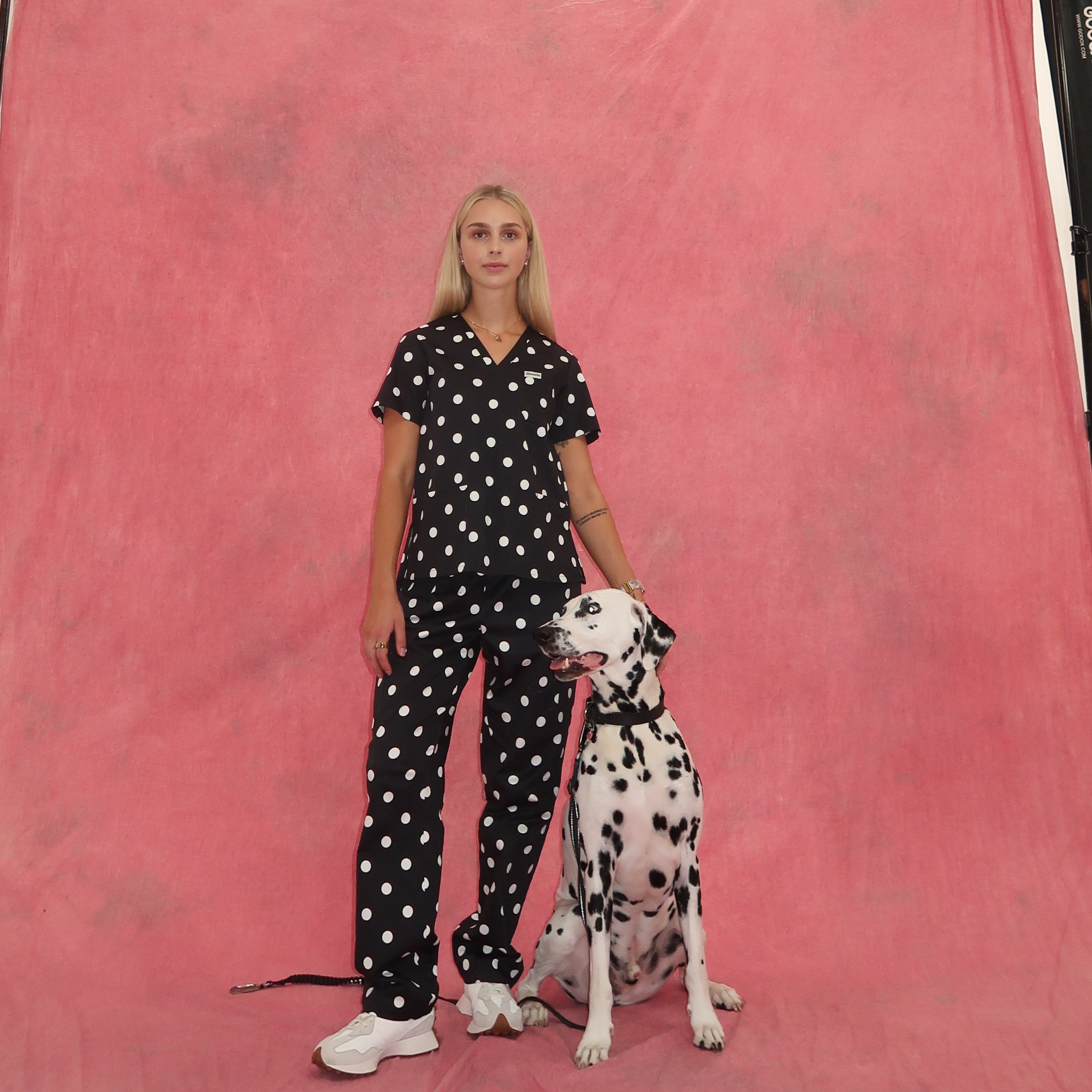 Woman in polka dot scrubs with a Dalmatian dog on a pink backdrop
