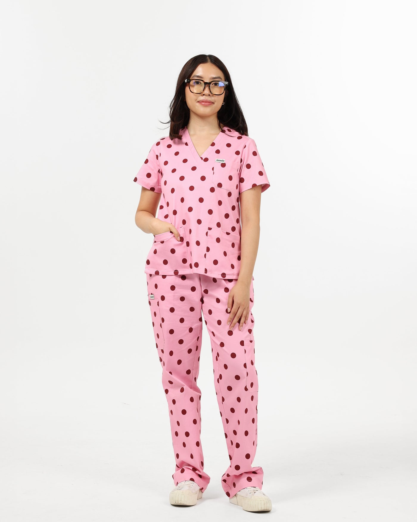 Person wearing a pink polka dot scrub set on a white background